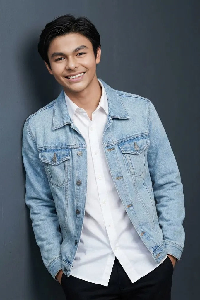 Man wearing a denim jacket over a white shirt against a gray background