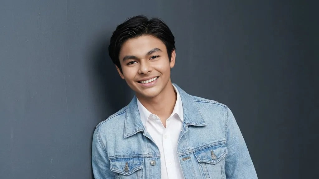 Man wearing a denim jacket over a white shirt against a gray background